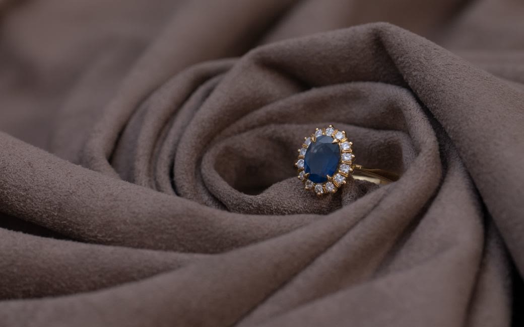 Anello in oro con zaffiro blu e contorno di diamanti su tessuto
